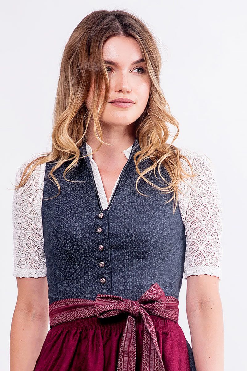 Dunkelblaues traditionelles Dirndl mit weißer Spitzenbluse und rotem Schürzengürtel.