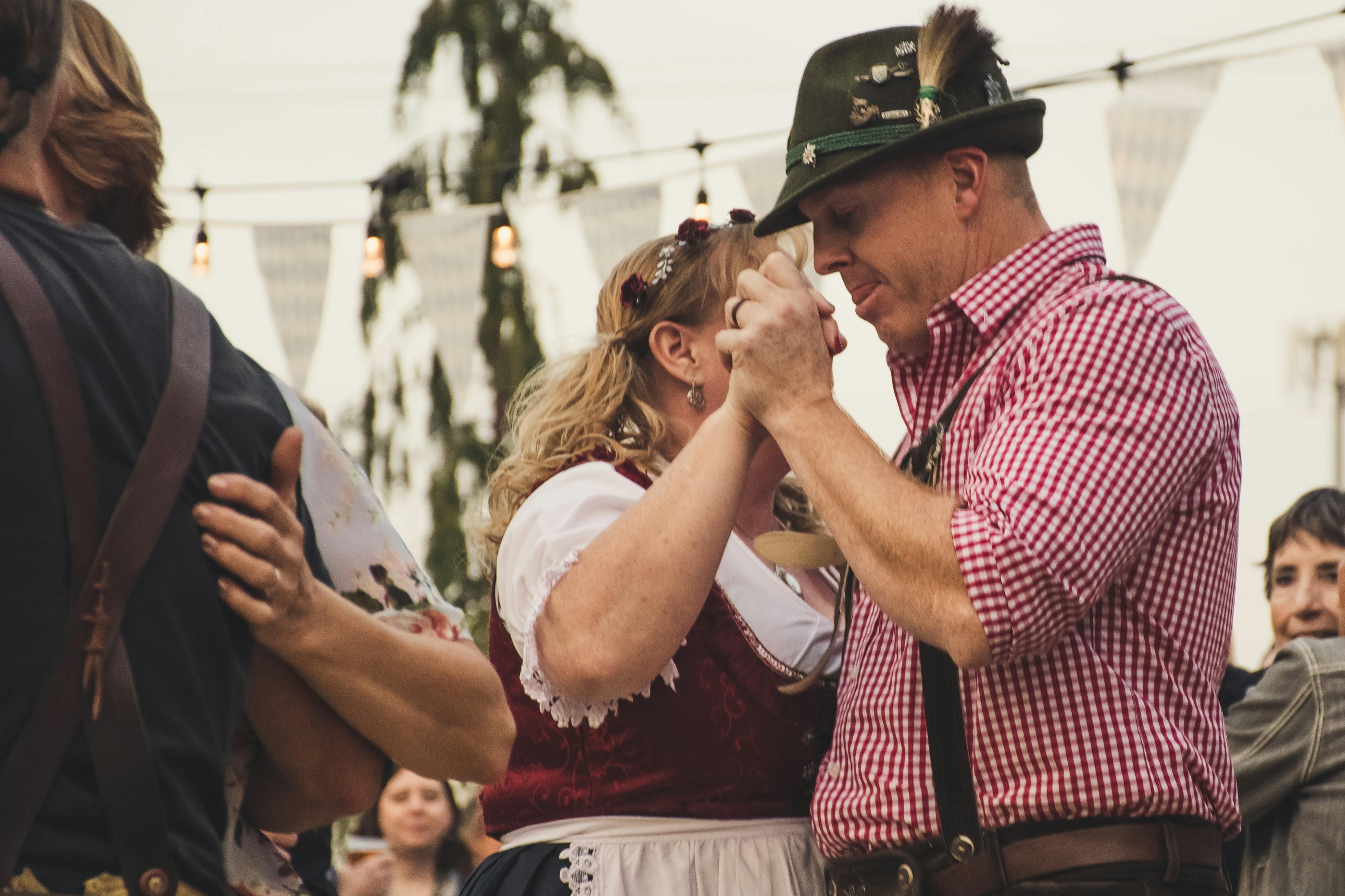 Menschen tanzen in Tracht mit Dirndl und Lederhose auf einem traditionellen Fest von MOSER Trachten.