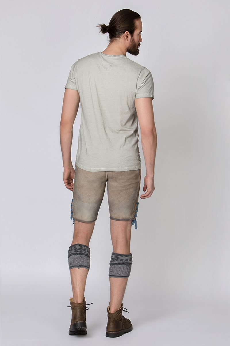 Ein Mann trägt moderne Lederhosen von MOSER Trachten mit grauen Kniestrümpfen.