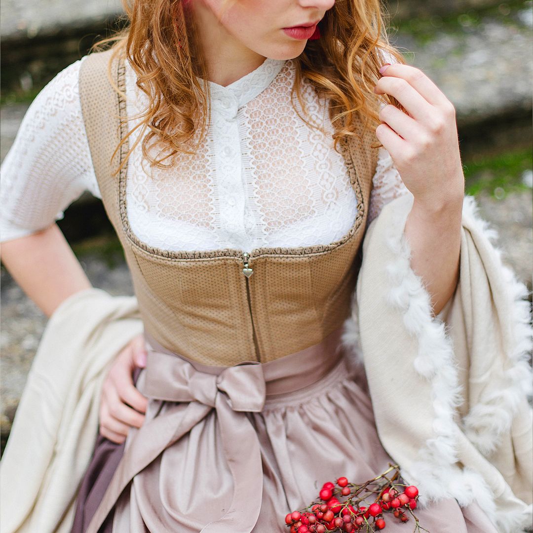 Elegantes Moser Dirndl mit weiß-karierter Bluse und roten Beeren als Accessoire.