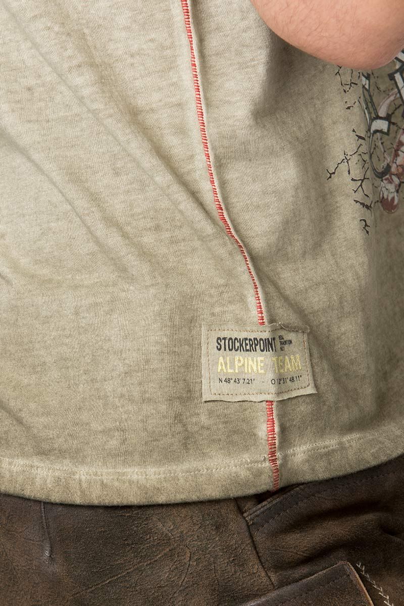 Beiges Trachten-Shirt von Stockerpoint mit roter Naht, kombiniert mit brauner Lederhose.