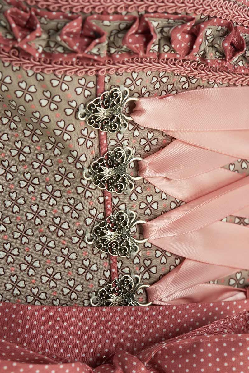 Rosa Dirndl-Mieder mit filigranem Muster und edlen Metallhaken, passend zur MOSER Trachtenmode.