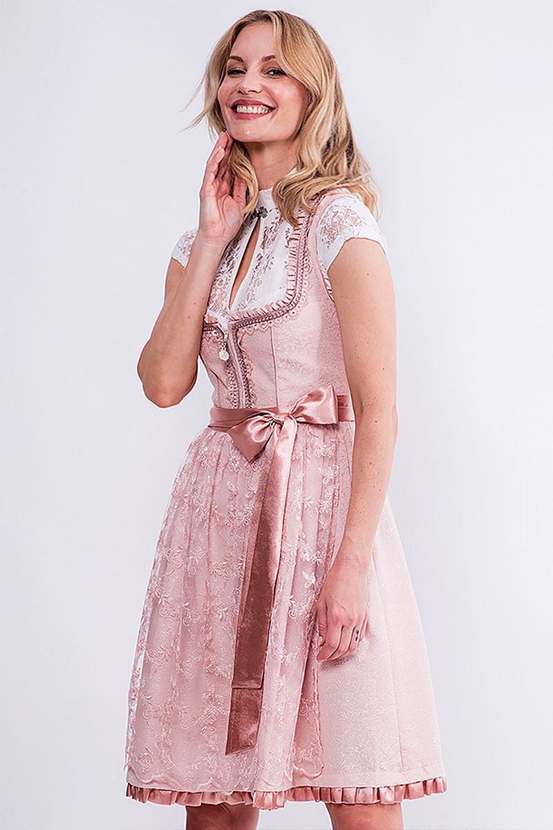 Eine Frau trägt ein elegantes rosa Dirndl von MOSER Trachten mit Spitzenbluse.